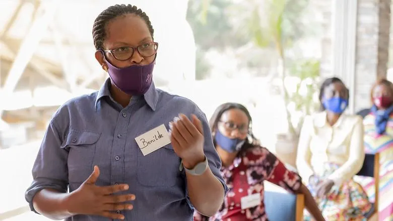 A woman in a face mask makes a point to a class of students.