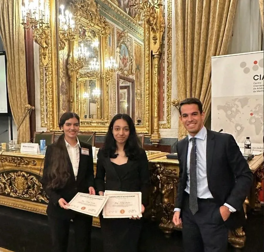 Sports arbitration- Three people smiling for the camera. Two people hold certificates. 