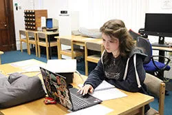 Student intern studying a book in a reading room