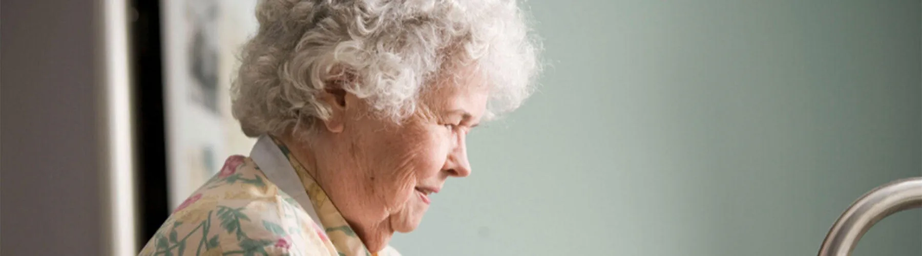 An older woman washes her hands in a sink