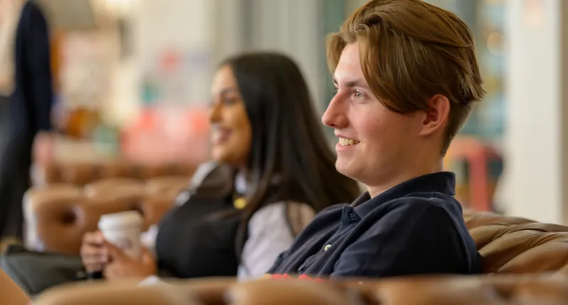 Two students sitting on a sofa talking.