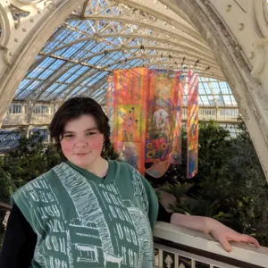 Alex in a greenhouse at Kew gardens, smiling at the camera.