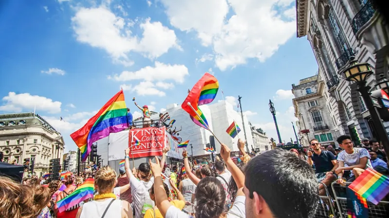 A crowd of people at the London Pride Parade holding pride flags