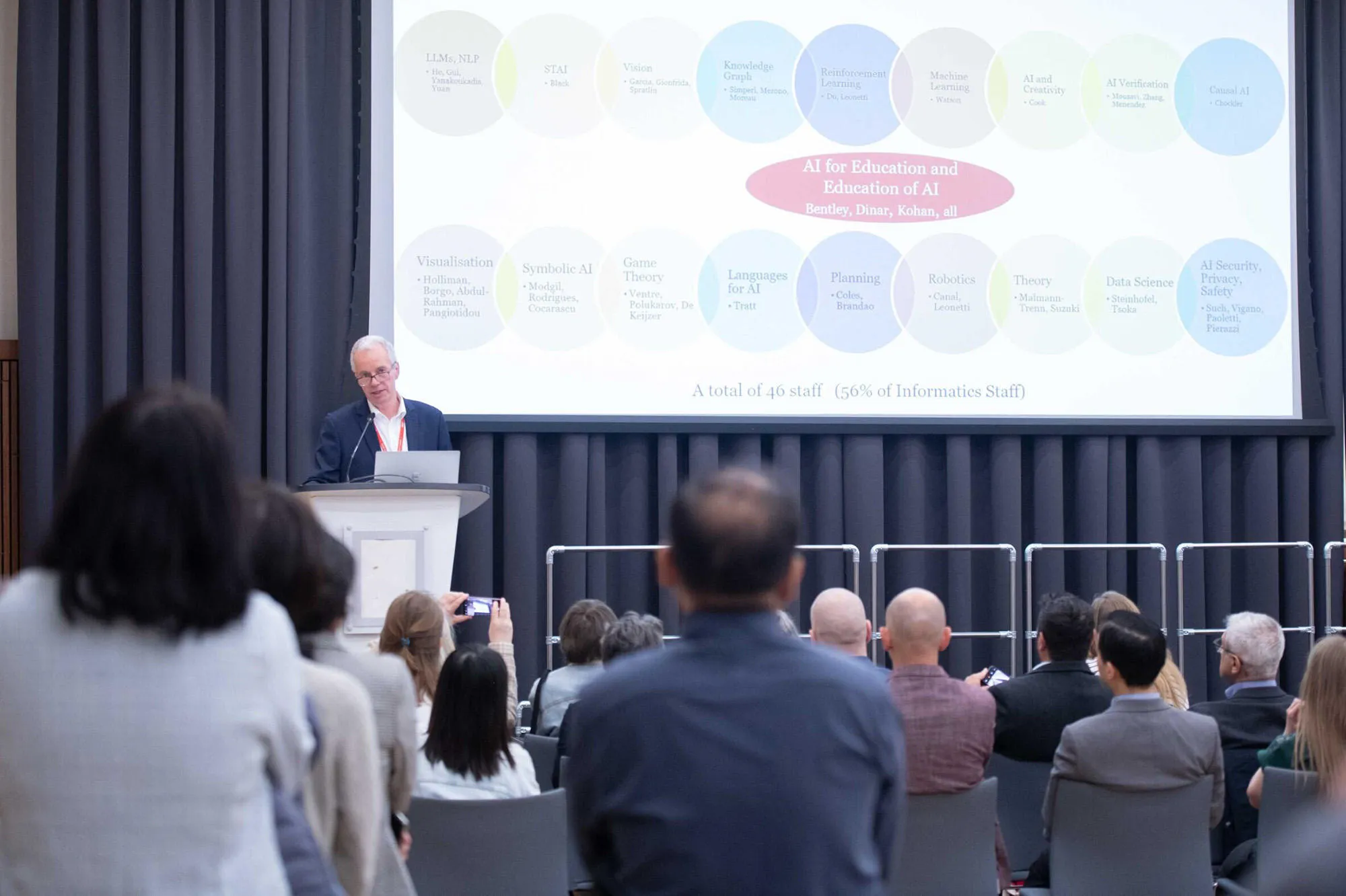 A man giving a speech on a pedestal in front of an audience