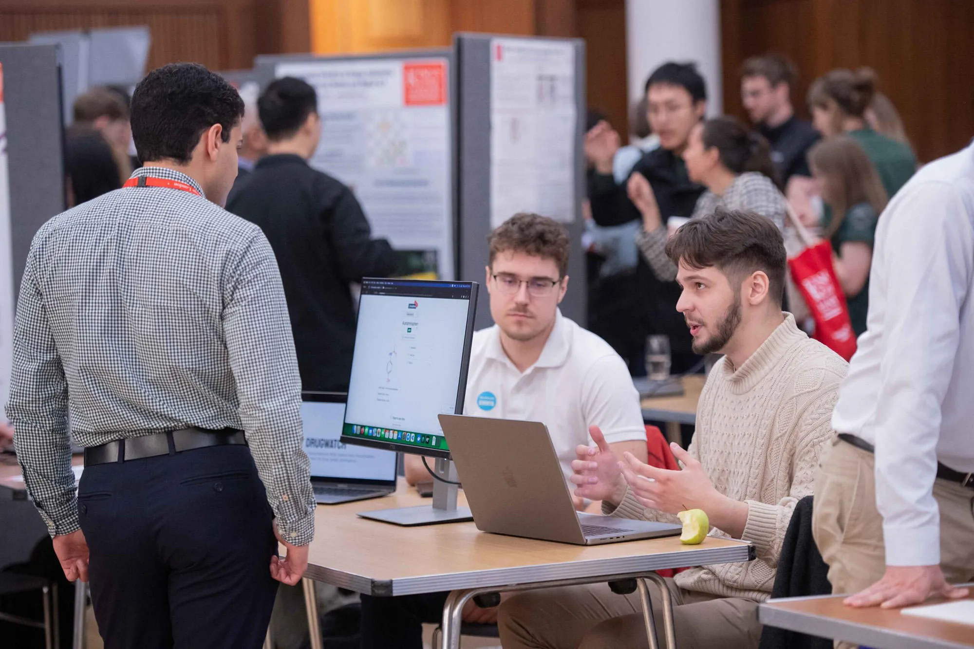 Two students talking about their research to a guest