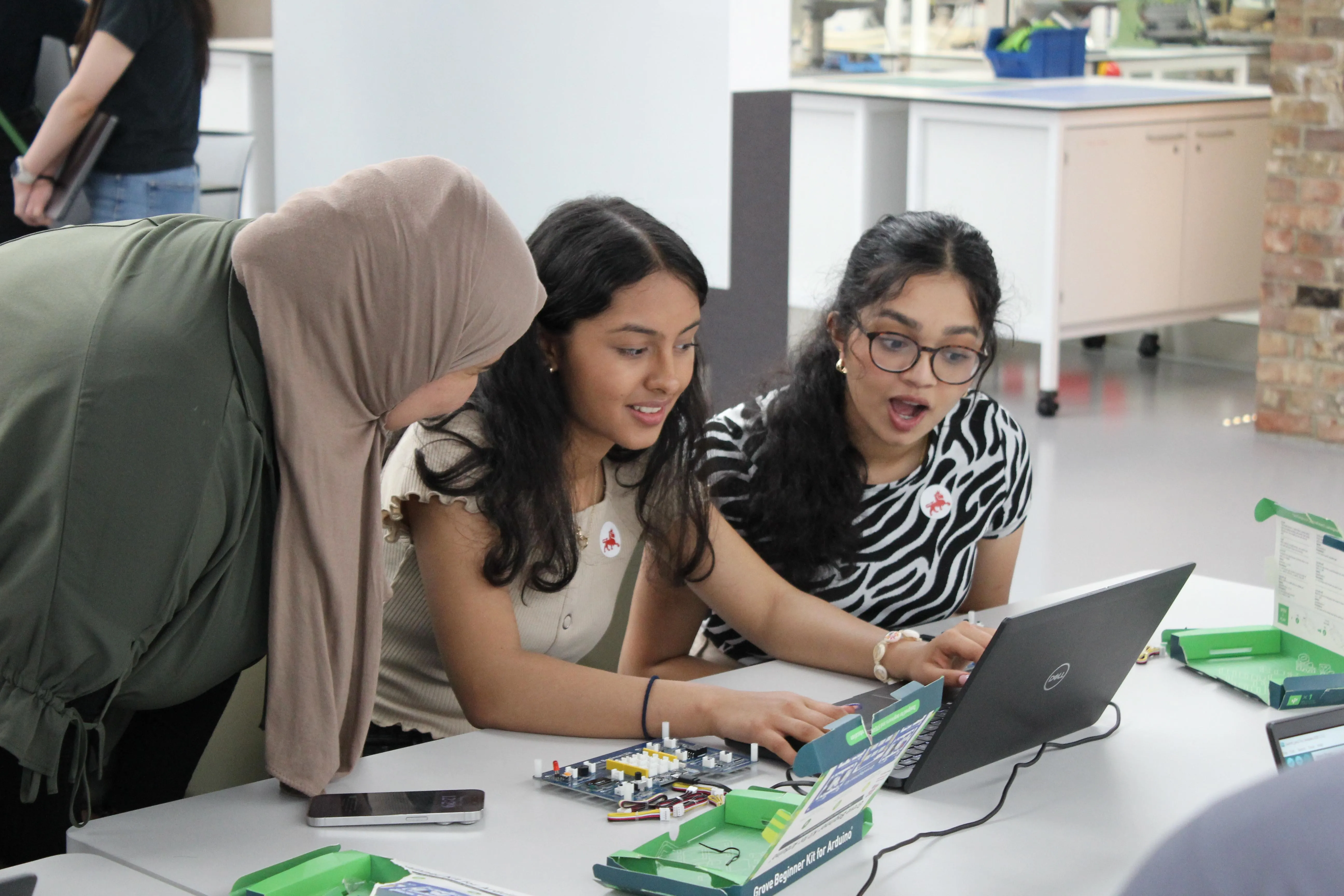 A woman is explaining something to two girls who are working on a computer