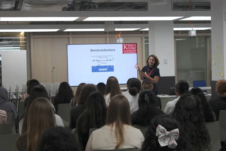 A woman is talking about semiconductors to a group of school girls