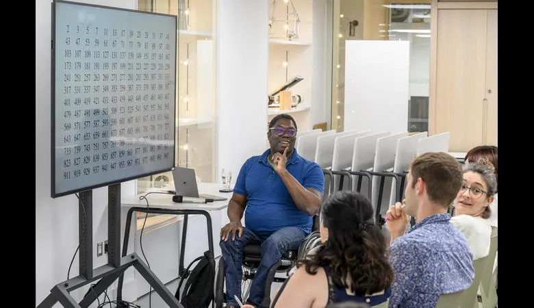 A presenter sits talking to a group