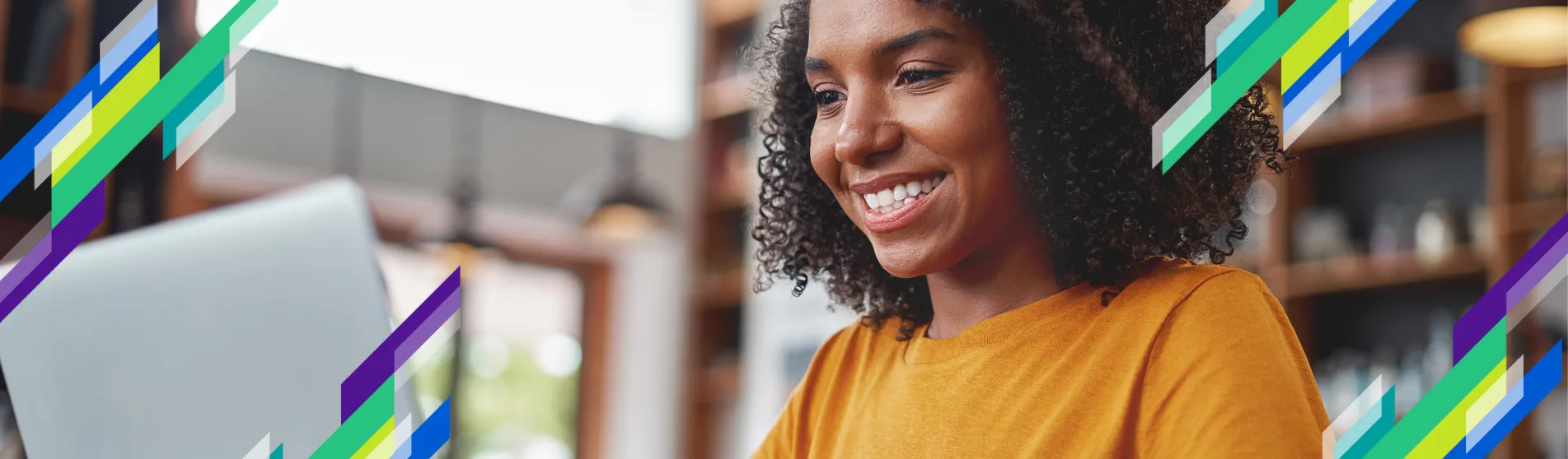 a woman sits smiling typing on a laptop.