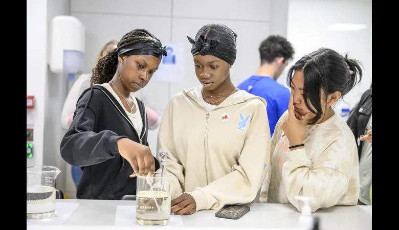 Three students pipette a liquid out a glass jar