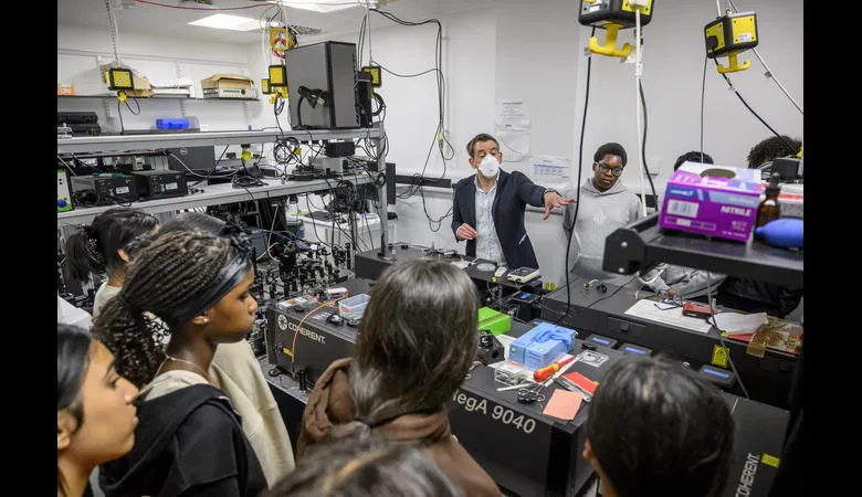Students stand in a busy research lab filled with electrical equipment
