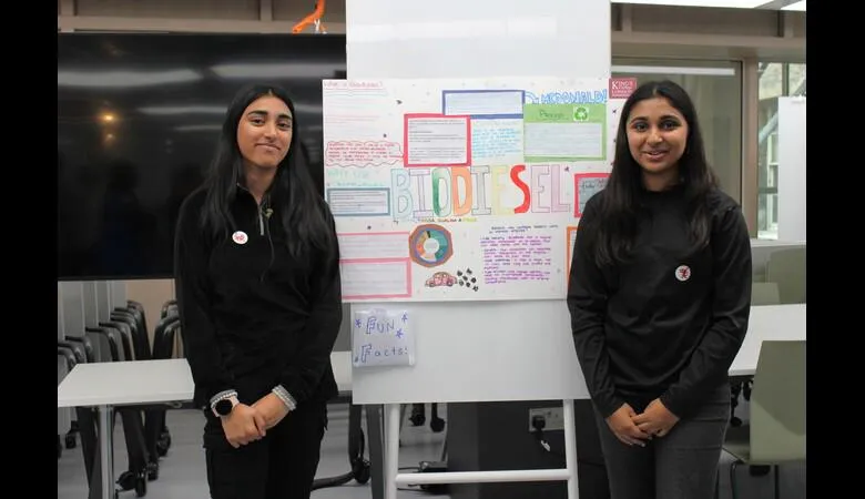 Two students stand next to a poster