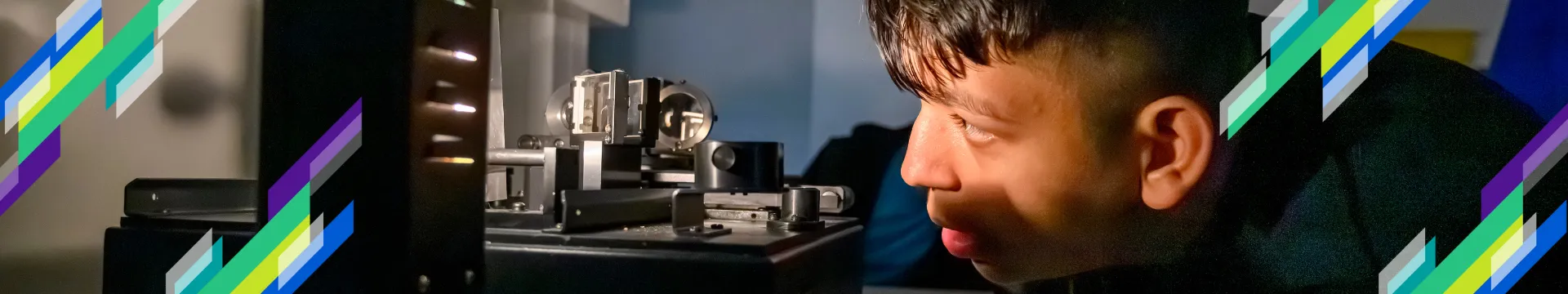 A boy looks at science experiment in the dark, with light from it shining on his face