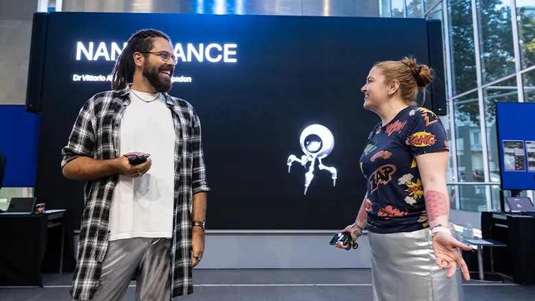 Vittorio Aita and Megan Grace-Hughes, the originators of the Nano Dance, stand in front of a large digital screen reading 'NANO DANCE'