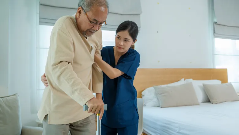 Woman supporting an elderly man standing up with a cane