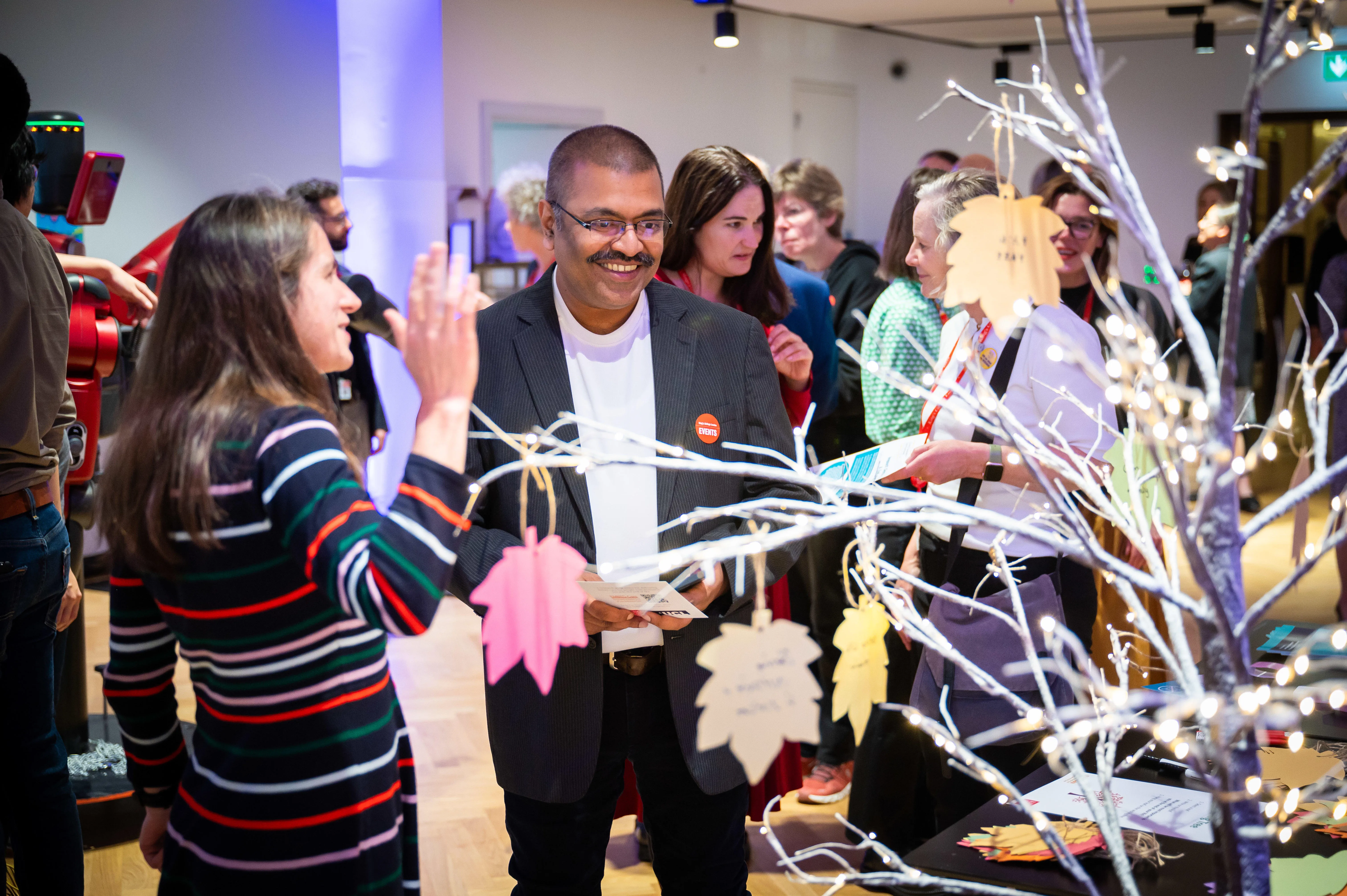 A group of people gathered around a stall at a reception event talking