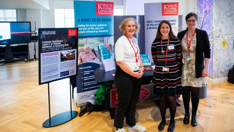 Professors associated with the Impact Centre stand in front of a stall explaining its work and impact