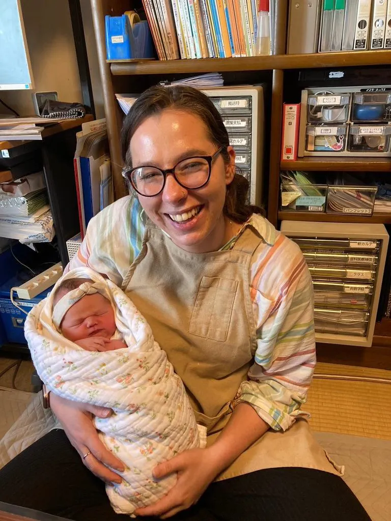 Kelly Whiting holding a baby while on placement in Japan