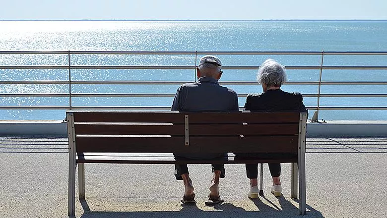 Elderly couple sitting on a bench by the sea