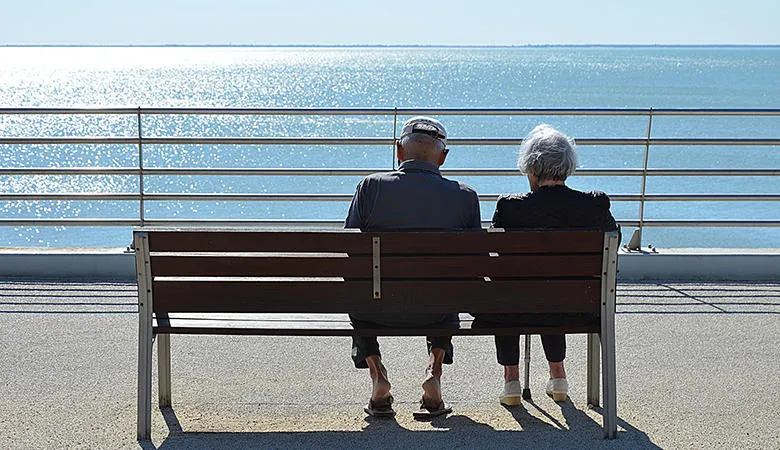 Elderly couple sitting on a bench by the sea