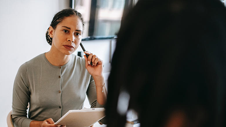 Woman sitting opposite a person holding a clipboard and pen