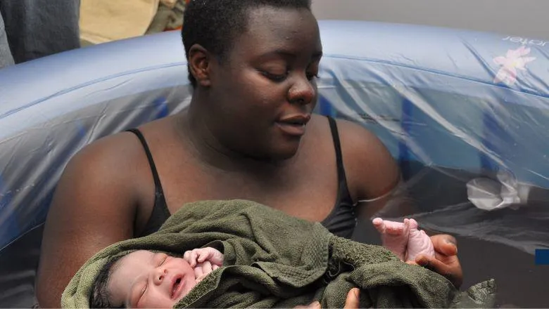 Mother cradling a newborn in a birthing pool.