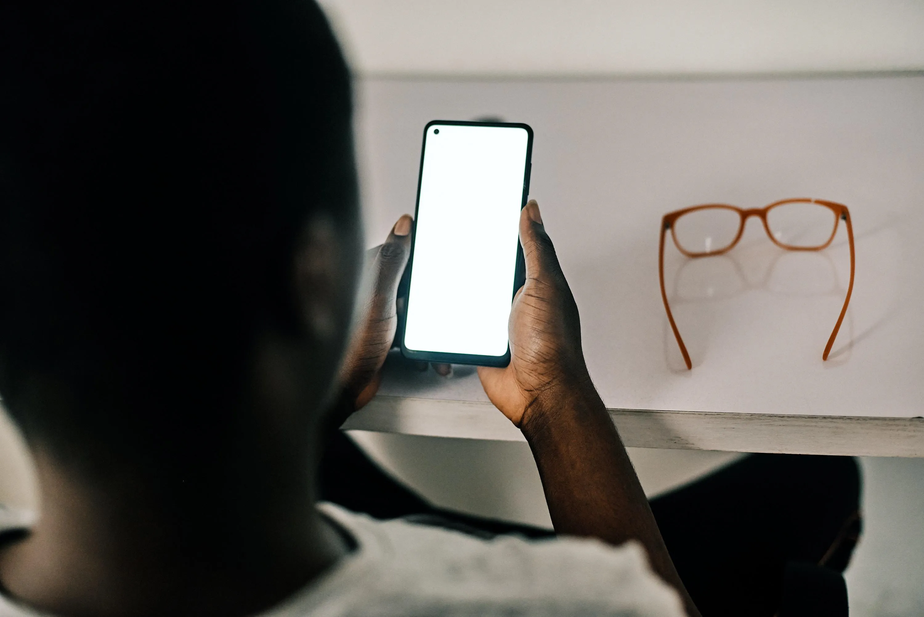 Man sits at table looking at mobile phone