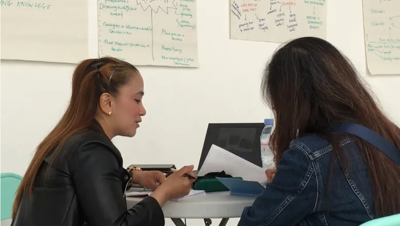 two women sitting and doing paperwork together