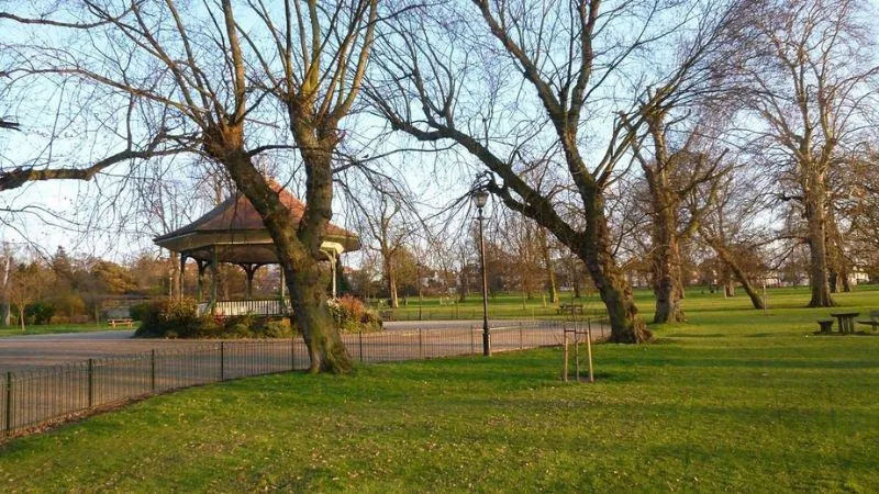 A picturesque park scene showcasing a gazebo with verdant trees providing a natural backdrop, perfect for leisure activities