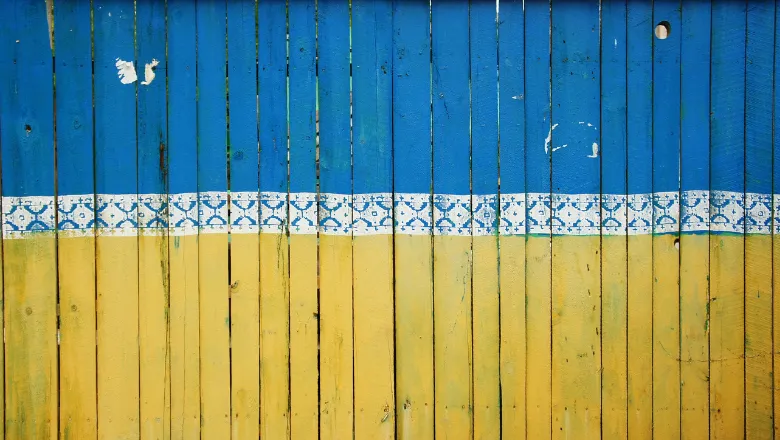 Blue and yellow fence with white patterned border in the middle, representing colours in the Ukranian flag.