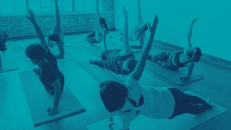 A diverse group of individuals practicing yoga together in a spacious, well-lit room, focusing on their poses.