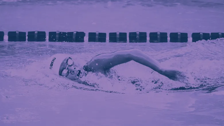 A woman wearing a swimming cap and goggles swimming in a pool. 