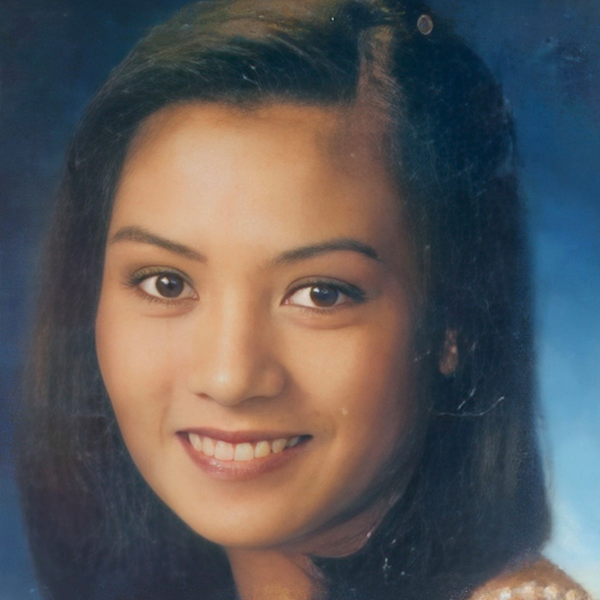 Josephine Ambalada smiles in front of a blue background