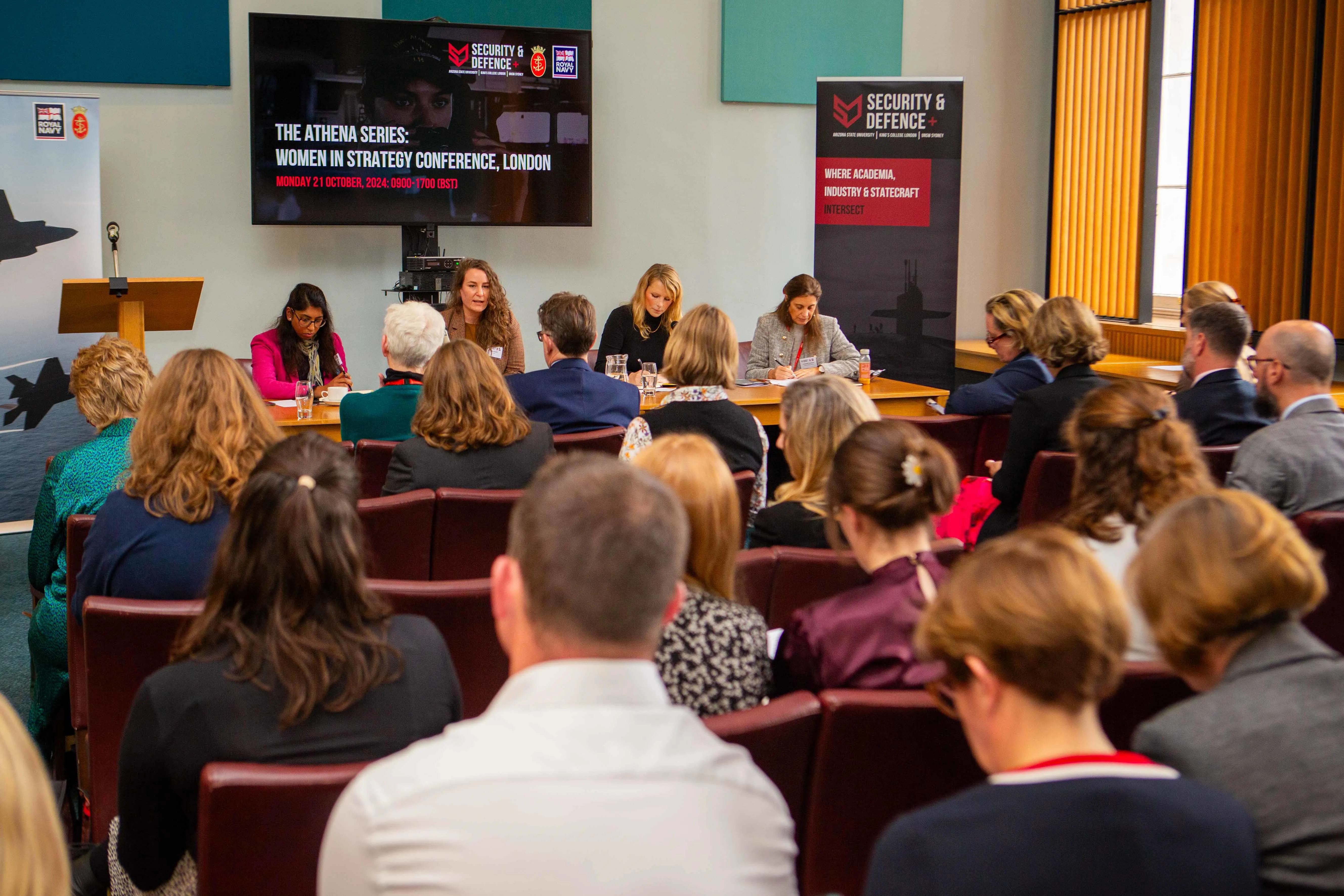 A panel of four people are sat at a table speaking to an audience