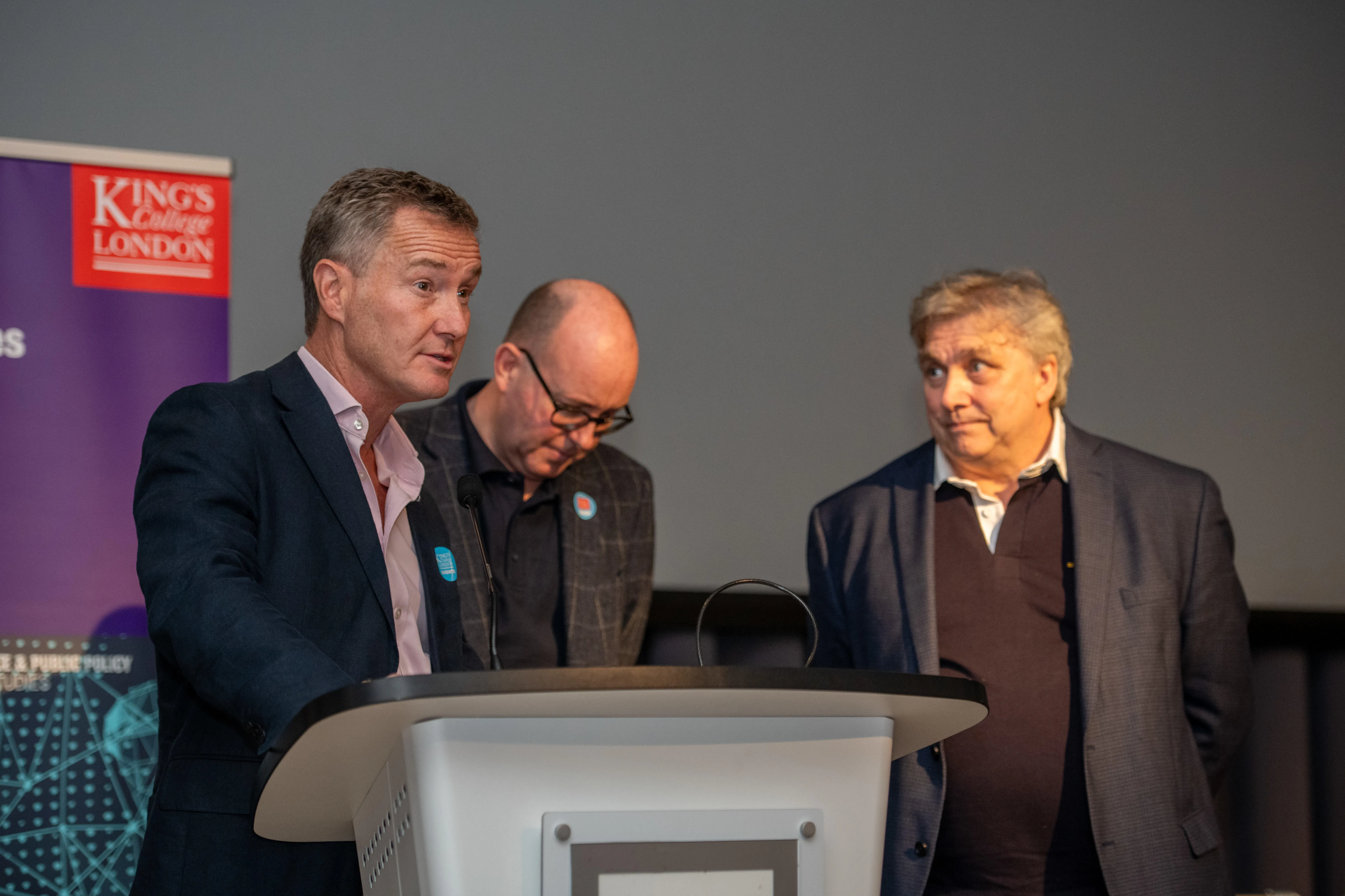 Major General Zac Stenning, Visiting Professor Andrew Stewart and Professor James Gow stand at lectern