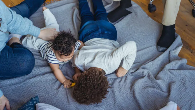 children on the floor with adults overseeing them