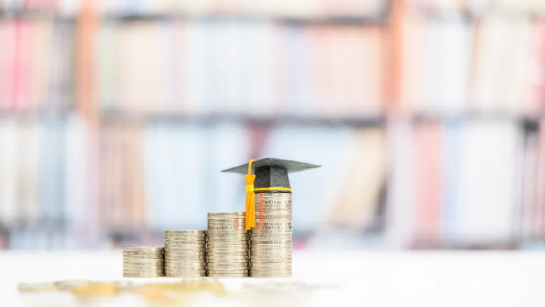 Graduation cap on the highest of four piles of coins