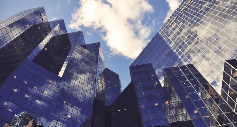 Looking up at glass buildings from the ground.