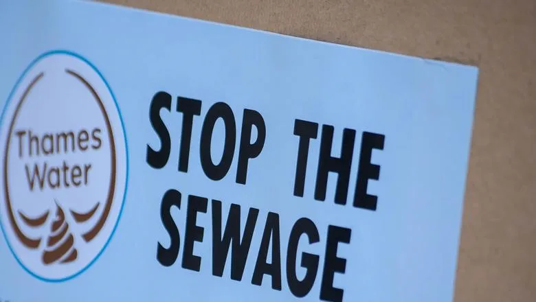 A protest sign which shows the Thames Water logo and text 'Stop the sewage - tell Thames water to cut the crap'