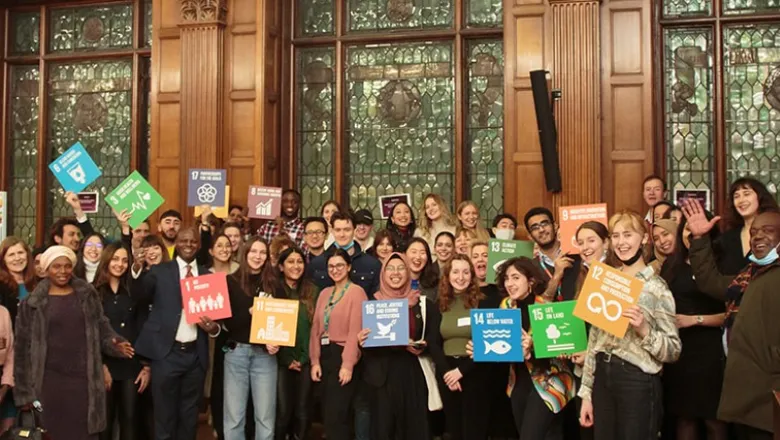 Sustainability group smiling at the camera holding up action signs