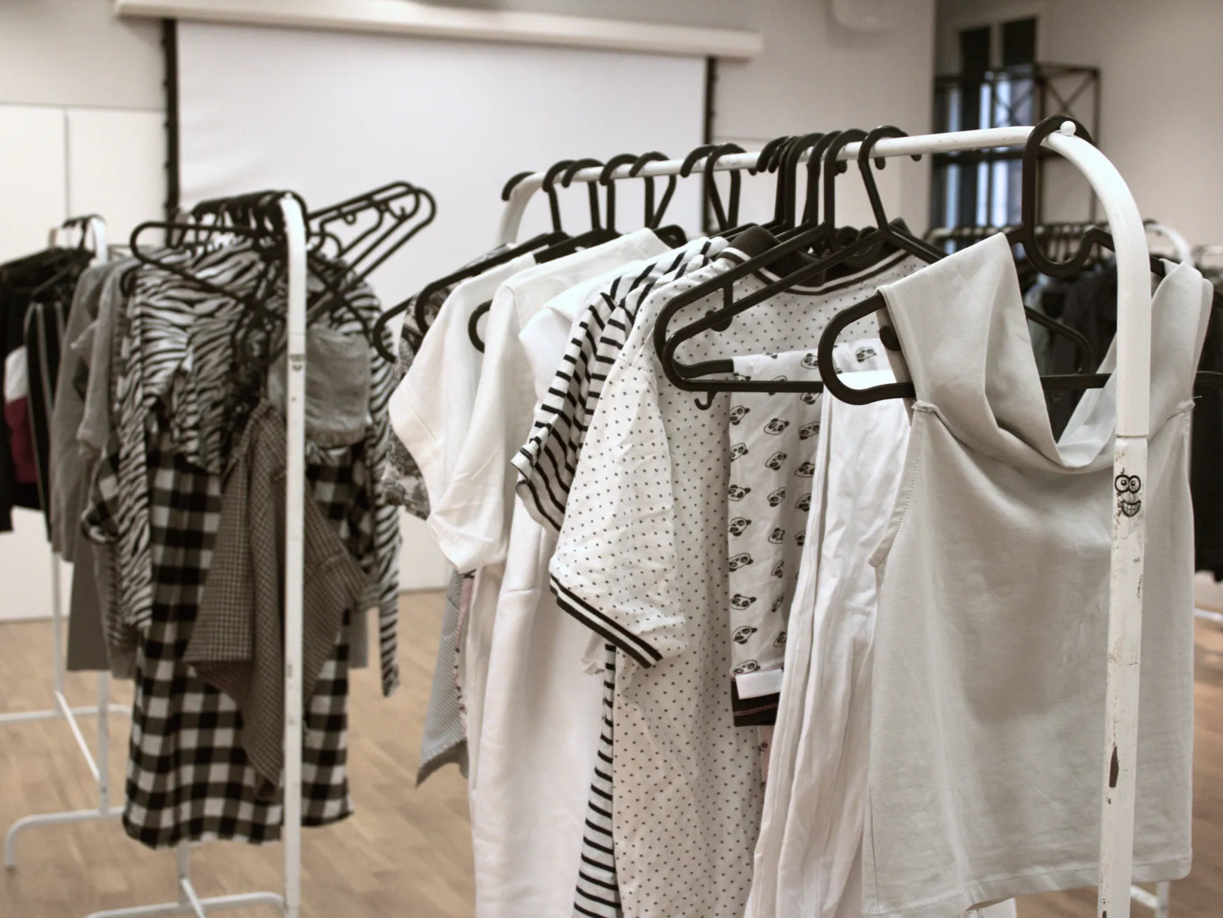 Racks of white and black clothes against a studio background