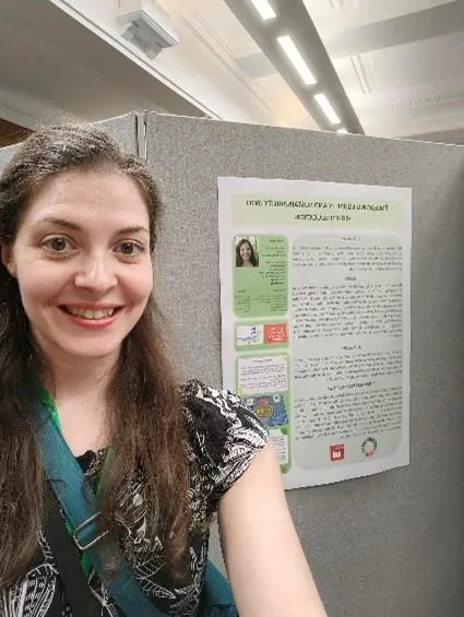 A woman standing in front of a grey board with a poster on it