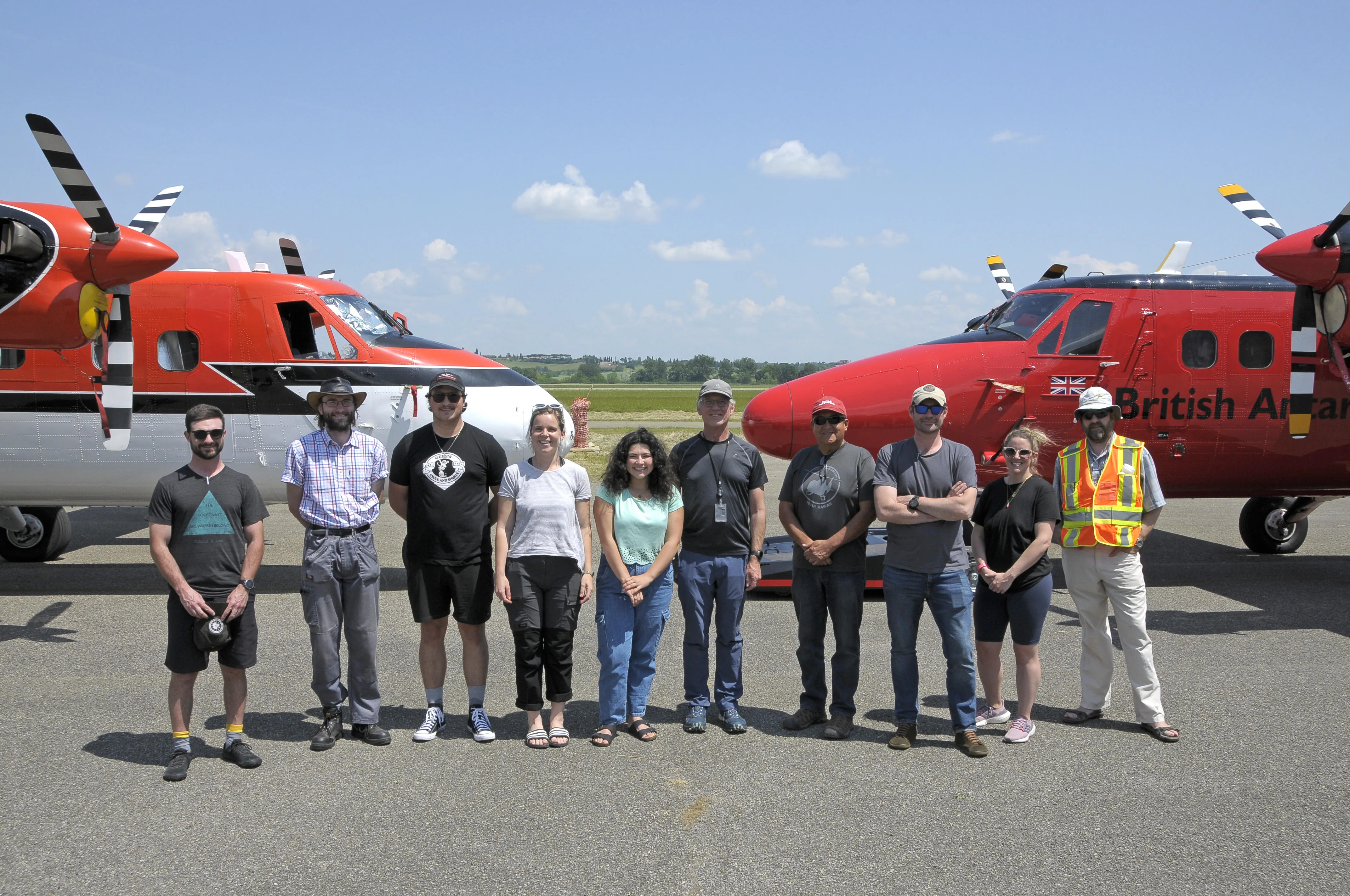 Researchers standing in front of red planes on a field