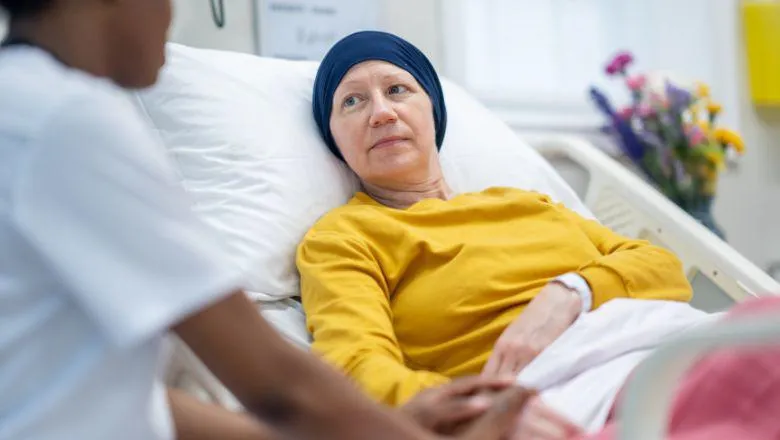 A sick woman in bed with a nurse by her side