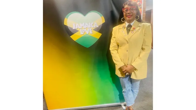 Image of Samantha Wright, stood in front of a sign that says 'Jamaica Love' 